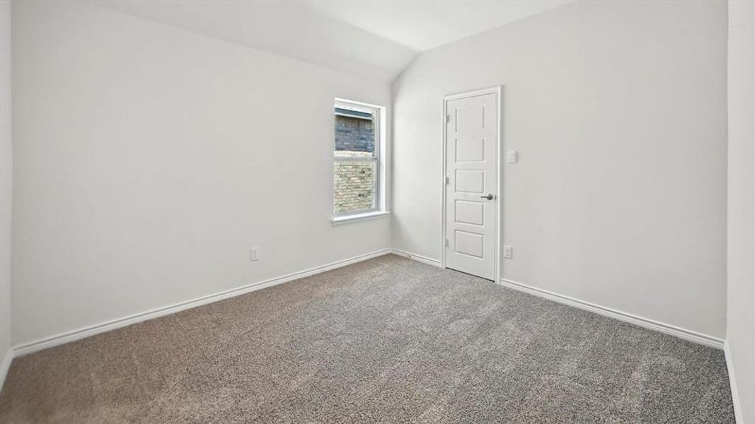 Carpeted spare room featuring lofted ceiling and baseboards