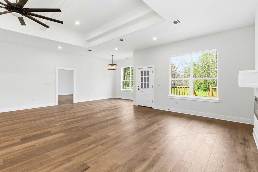 An airy living area with recessed lighting and warm wood flooring welcomes natural light through large windows. An airy living area with recessed lighting and warm wood flooring welcomes natural light through large windows.