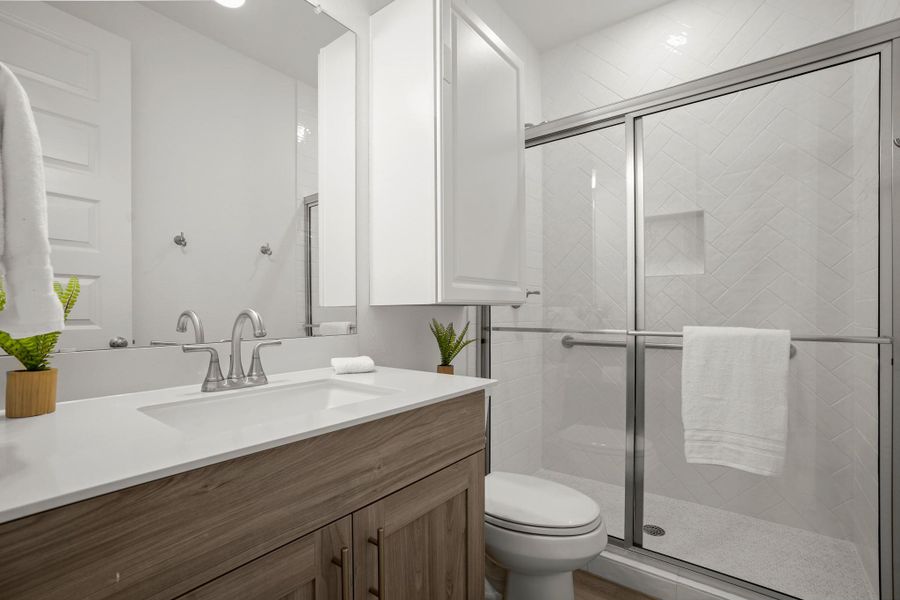 The bathroom in the multi-gen space has a walk in shower with grab bars and a spacious glass enclosure.