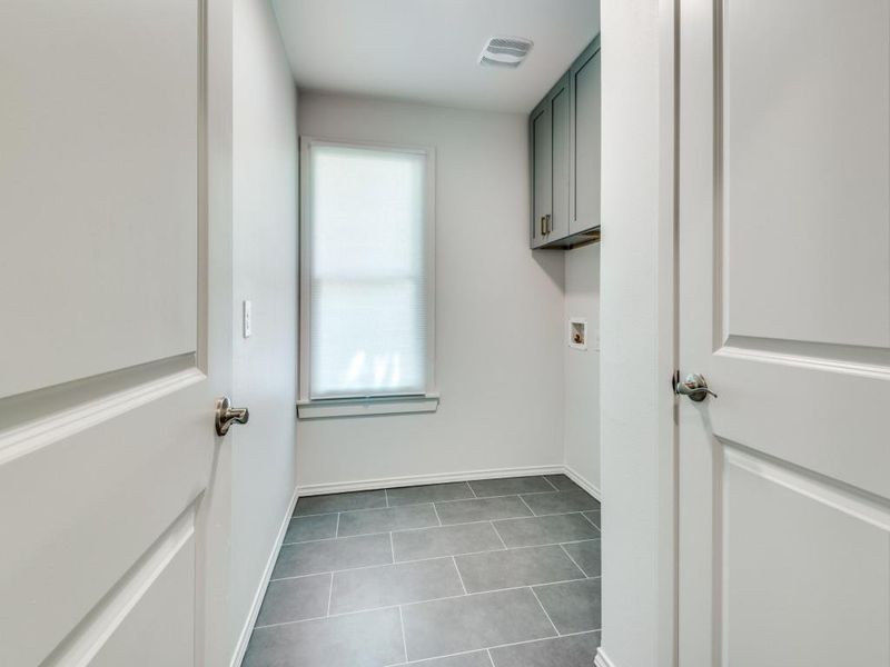 Laundry room with dark tile patterned floors, cabinets, and hookup for a washing machine