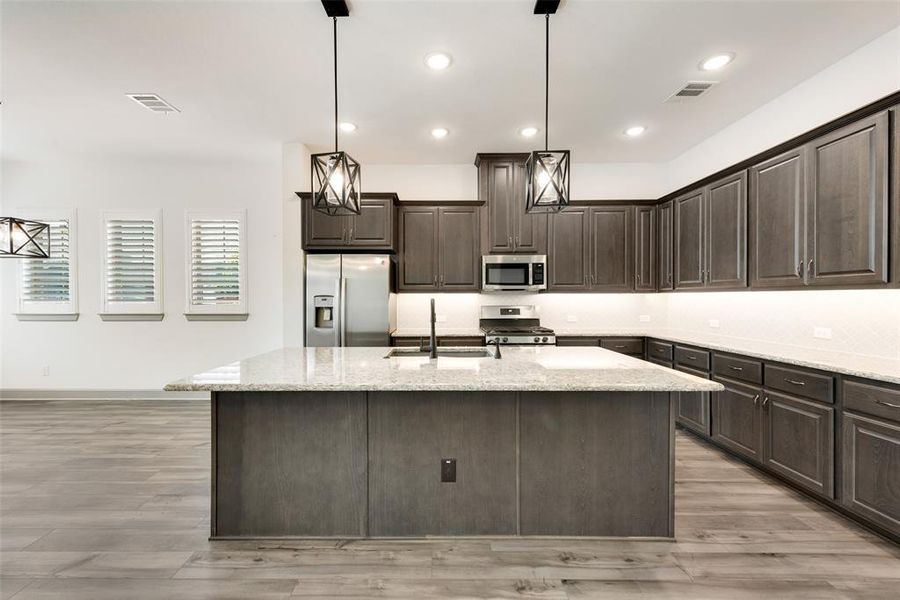 Kitchen with an island with sink, dark brown cabinets, appliances with stainless steel finishes, and sink