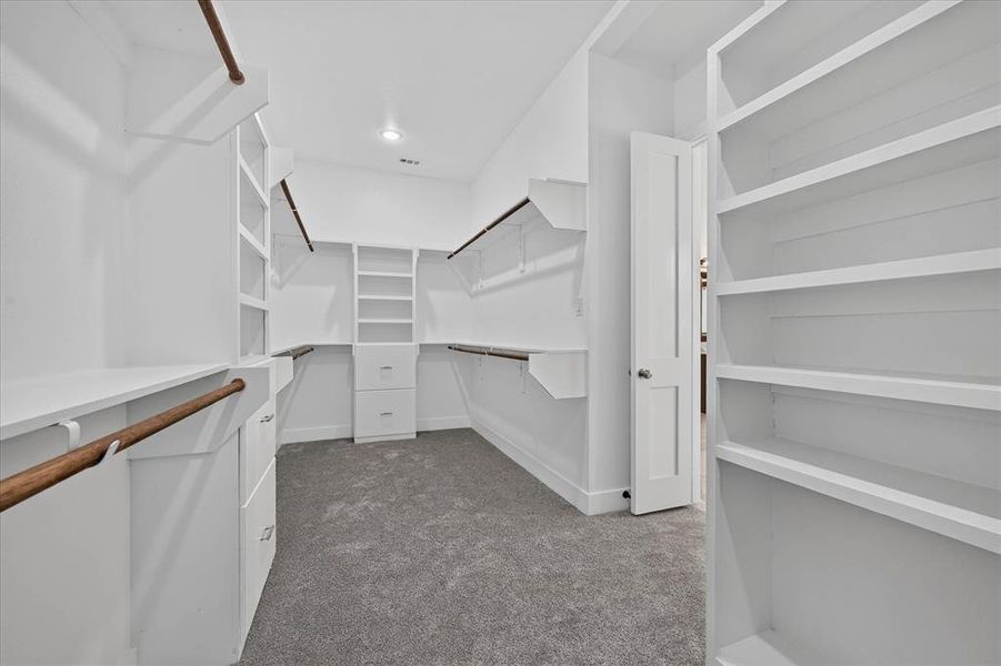 Spacious walk-in closet featuring extensive built-in shelving, hanging rods, and integrated drawer storage Spacious walk-in closet featuring extensive built-in shelving, hanging rods, and integrated drawer storage