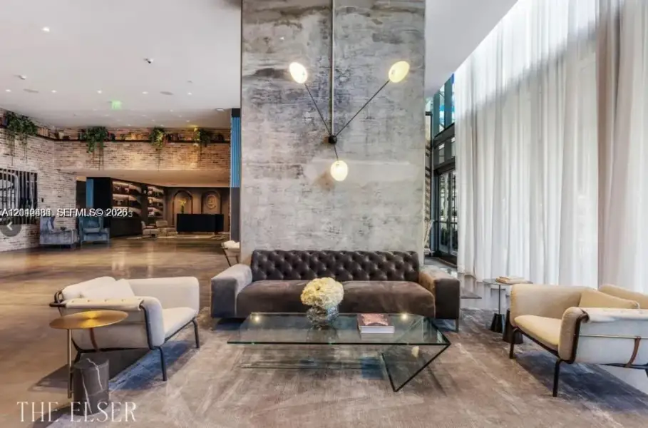 Exposed concrete accent wall with multi-arm fixture, floor-to-ceiling drapery, polished concrete flooring, and decorative brick masonry wall Exposed concrete accent wall with multi-arm fixture, floor-to-ceiling drapery, polished concrete flooring, and decorative brick masonry wall