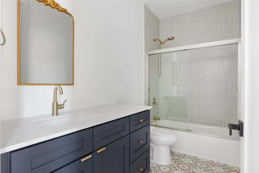 Bathroom with vanity, shower / bath combination with glass door, and light tile patterned floors Bathroom with vanity, shower / bath combination with glass door, and light tile patterned floors