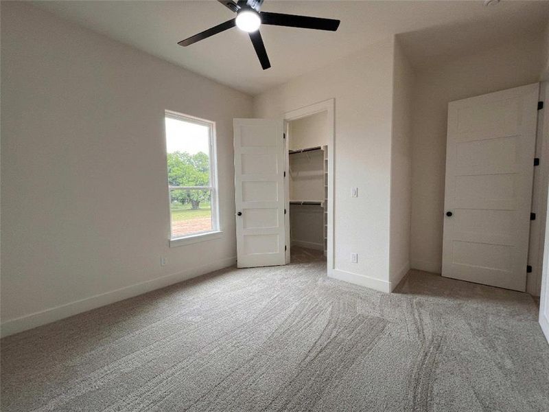 Carpeted room with a modern ceiling fan, a window, and a built-in closet with shelving