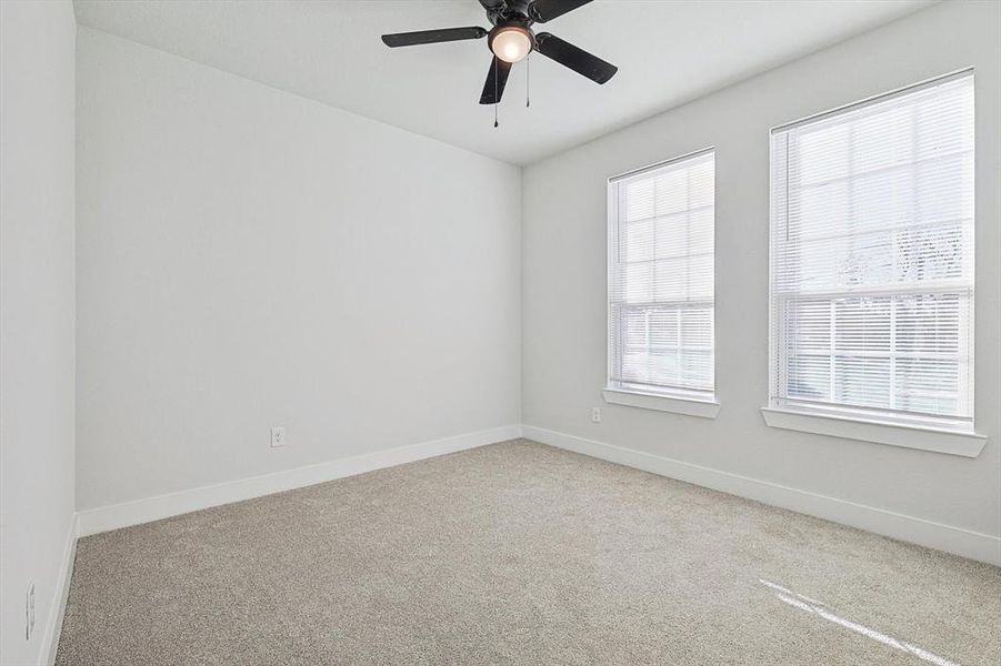 Carpeted spare room featuring ceiling fan