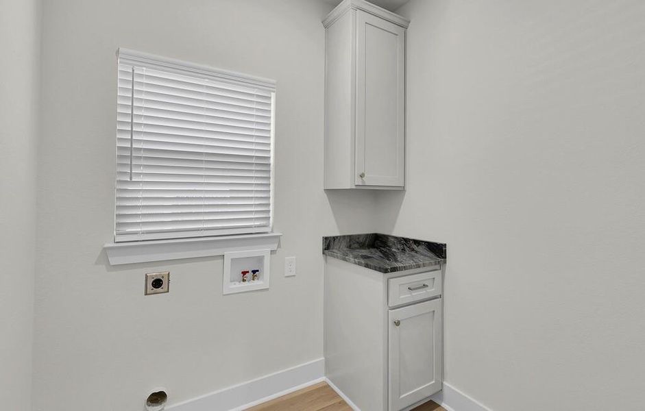 Laundry area featuring hookup for a washing machine, hookup for an electric dryer, light wood finished floors, and cabinet space
