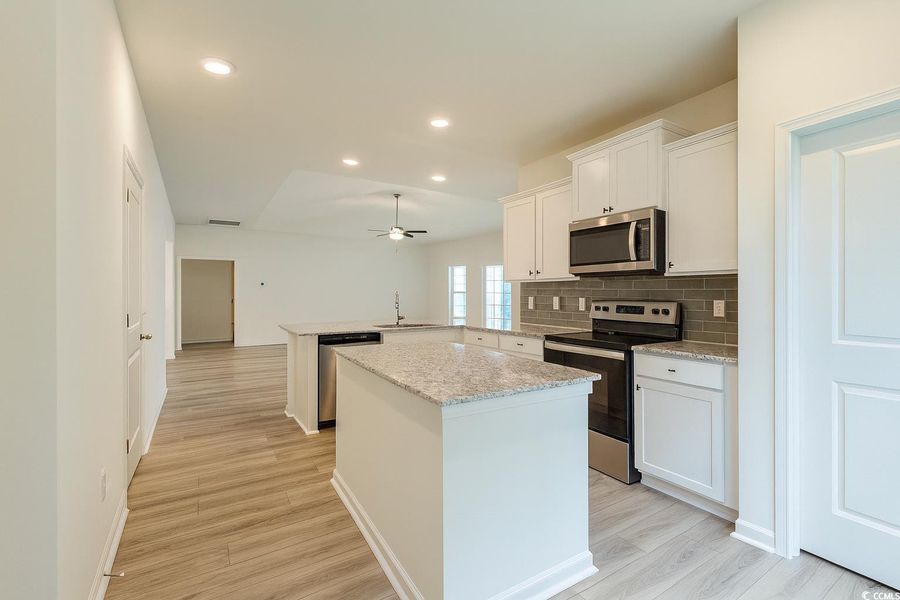 Kitchen with a peninsula, appliances with stainless steel finishes, recessed lighting, backsplash, and a kitchen island