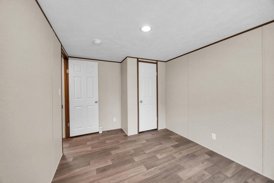 Unfurnished bedroom featuring wood finished floors, a closet, recessed lighting, and crown molding