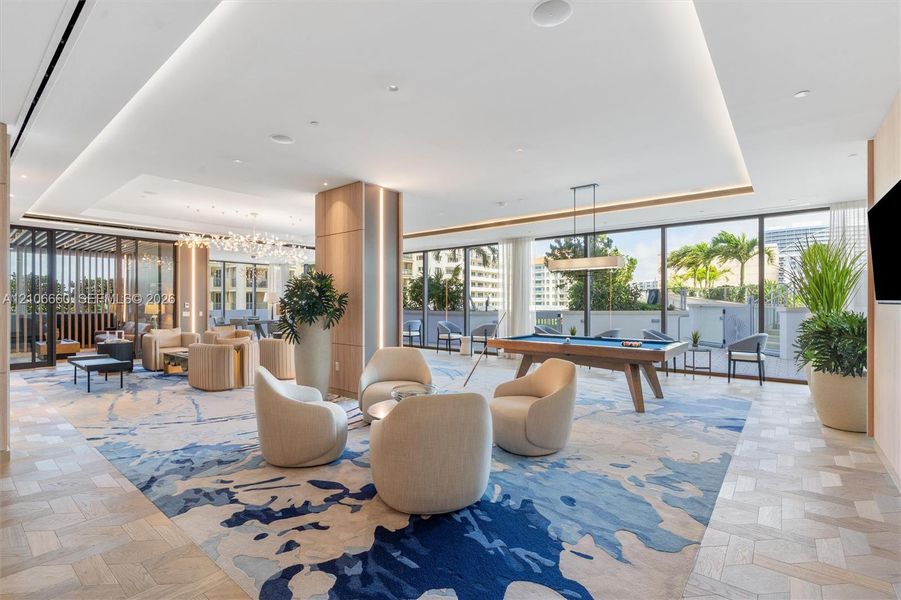 Expansive open-concept space featuring herringbone-patterned wood-finish flooring, floor-to-ceiling glass paneling, recessed cove lighting, and floor-to-ceiling wooden column detailing