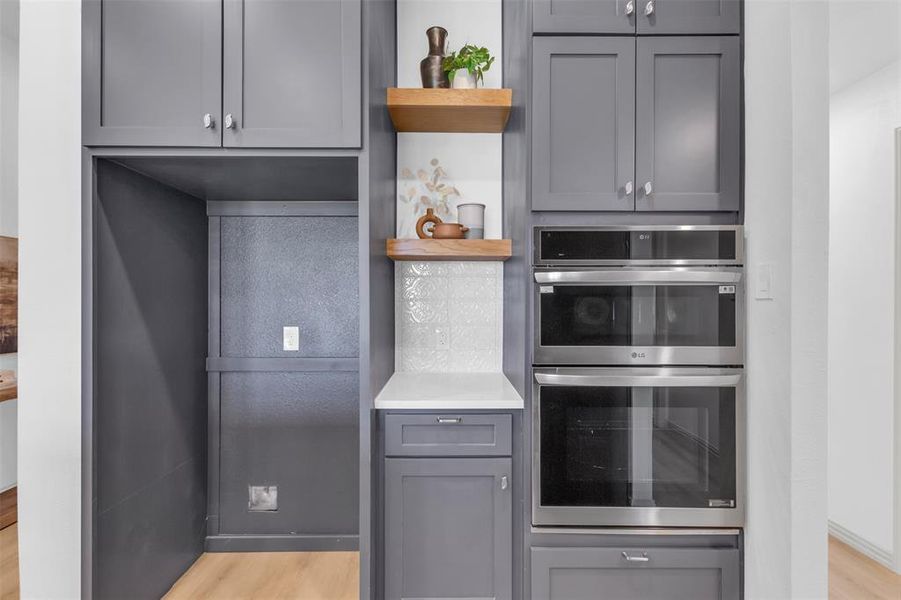 Kitchen featuring gray cabinets, open shelves, light wood-style floors, and stainless steel double oven Kitchen featuring gray cabinets, open shelves, light wood-style floors, and stainless steel double oven