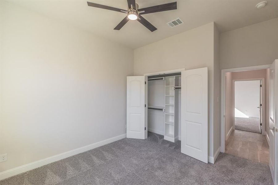 Unfurnished bedroom featuring carpet, ceiling fan, and a closet