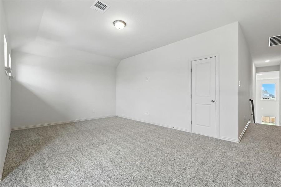 Carpeted spare room with baseboards and vaulted ceiling