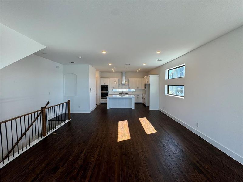 Unfurnished living room with sink and dark wood-type flooring