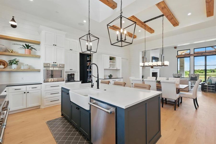 Kitchen featuring stainless steel appliances, open shelves, a chandelier, beamed ceiling, and light wood-style floors Kitchen featuring stainless steel appliances, open shelves, a chandelier, beamed ceiling, and light wood-style floors