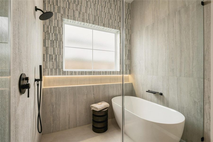 A private water closet is finished with full-height designer tile and natural light, carrying the primary bath’s refined material palette through every detail.