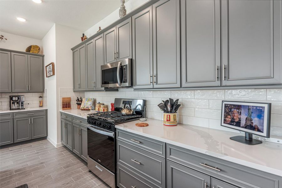 Sleek kitchen with modern gray cabinetry, stainless steel appliances, and elegant subway tile backsplash offering a stylish and functional cooking space.