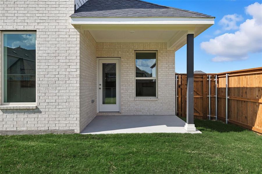 View of exterior entry with a patio, brick siding, and a shingled roof View of exterior entry with a patio, brick siding, and a shingled roof