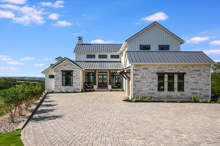 Modern farmhouse style home featuring stone siding, a chimney, board and batten siding, decorative driveway, and french doors Modern farmhouse style home featuring stone siding, a chimney, board and batten siding, decorative driveway, and french doors