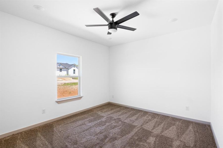 Empty room featuring carpet flooring, baseboards, and ceiling fan Empty room featuring carpet flooring, baseboards, and ceiling fan