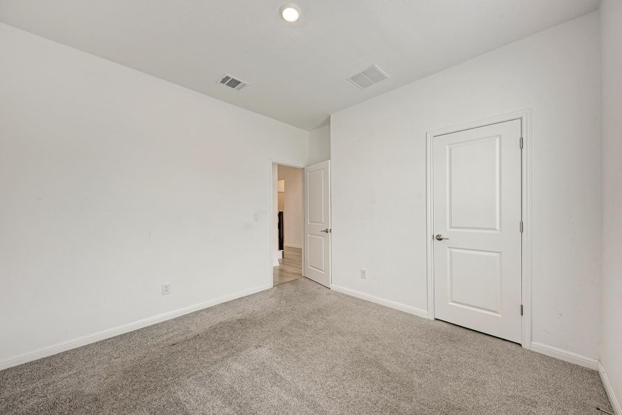 A well-lit bedroom with fresh carpet, offering a versatile space for rest or productivity.