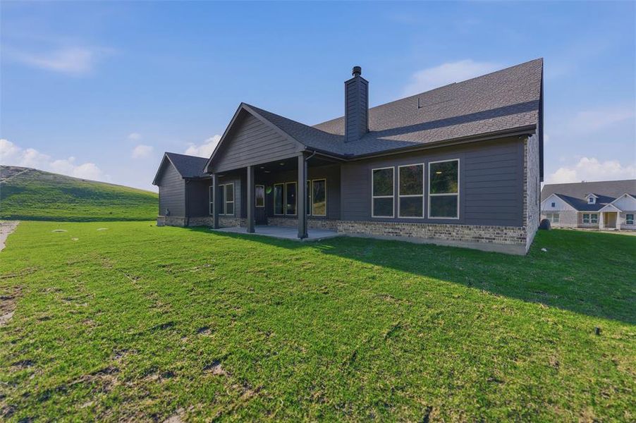 Back of property with a patio area, a yard, a chimney, and brick siding