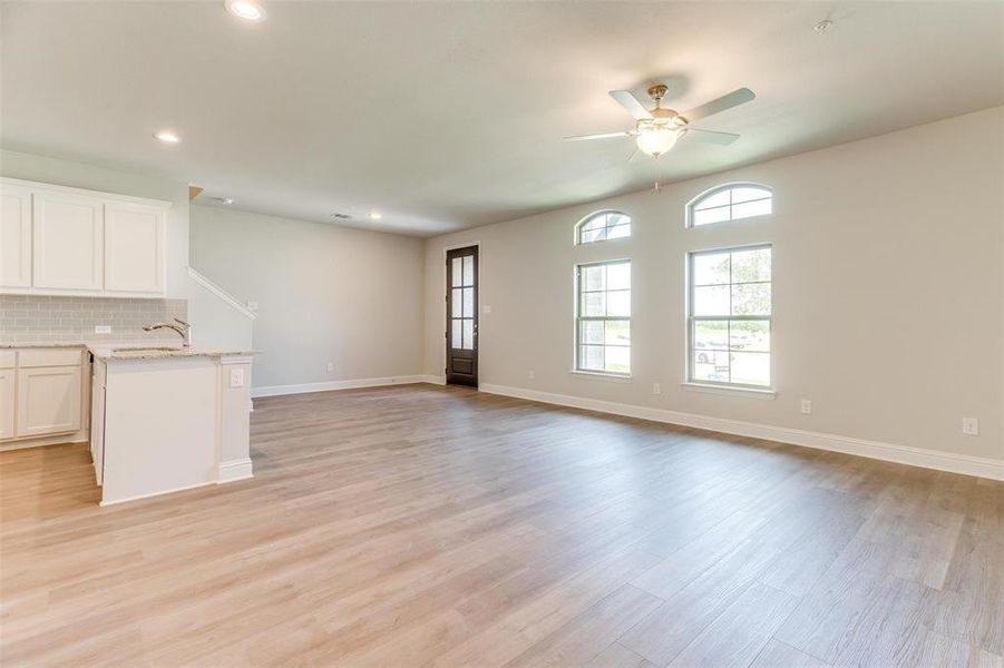 Unfurnished living room featuring ceiling fan and light hardwood / wood-style floors