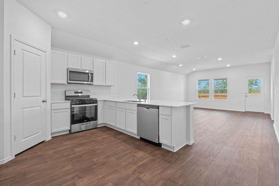 Kitchen with stainless steel appliances, white cabinets, recessed lighting, a peninsula, and dark wood-type flooring Kitchen with stainless steel appliances, white cabinets, recessed lighting, a peninsula, and dark wood-type flooring