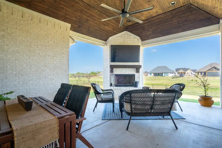 View of patio with a large fireplace, a ceiling fan, an outdoor living / dining area, and a residential view View of patio with a large fireplace, a ceiling fan, an outdoor living / dining area, and a residential view