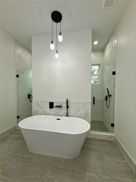 This modern bathroom features a sleek freestanding bathtub, elegant marble tile accents, and a spacious glass-enclosed shower. The pendant lighting adds a stylish touch to the contemporary design. This modern bathroom features a sleek freestanding bathtub, elegant marble tile accents, and a spacious glass-enclosed shower. The pendant lighting adds a stylish touch to the contemporary design.