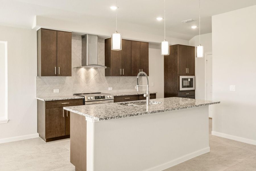 Kitchen with dark wood cabinets, granite island, stainless steel range, and pendant lights