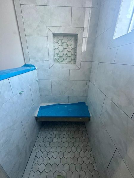 Full bath featuring a tile shower and tile walls Full bath featuring a tile shower and tile walls