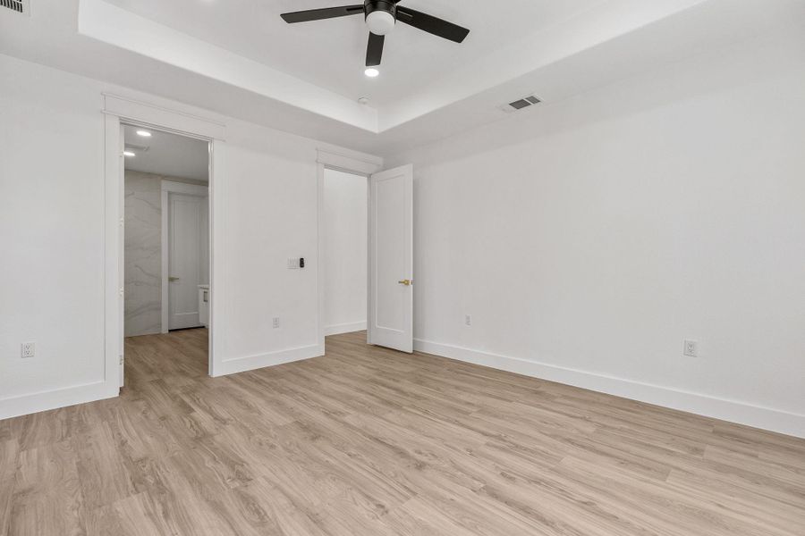 Unfurnished bedroom featuring recessed lighting, ceiling fan, a raised ceiling, and light wood-style flooring