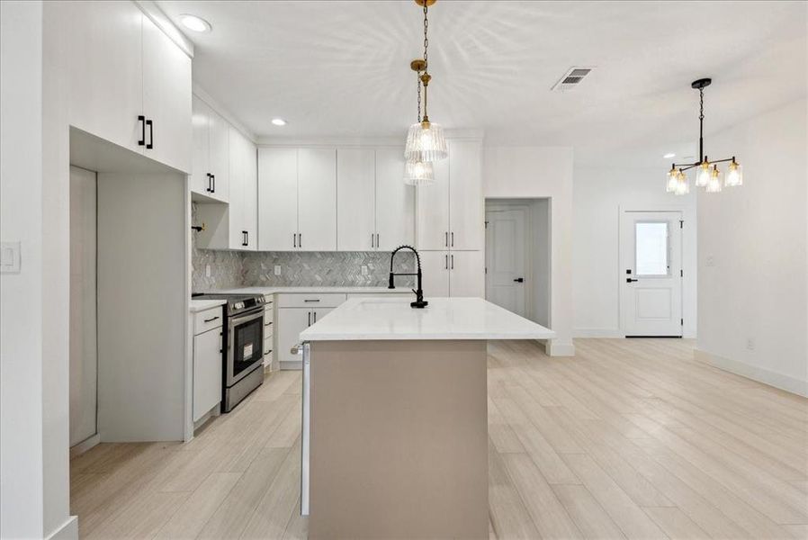 Kitchen with white cabinetry, hanging light fixtures, sink, and stainless steel electric range oven