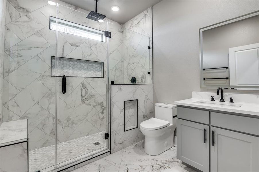 Bathroom with vanity, a marble finish shower, light marble finish floors, and recessed lighting