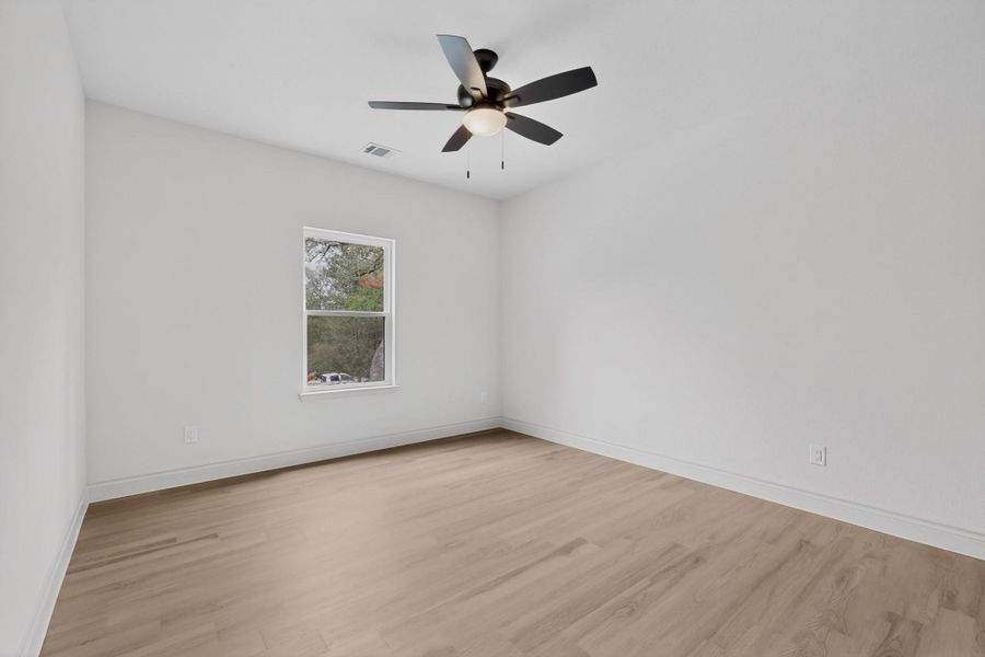 Bright interior space featuring wood-finish flooring, white baseboards, and a contemporary ceiling fan with integrated lighting Bright interior space featuring wood-finish flooring, white baseboards, and a contemporary ceiling fan with integrated lighting