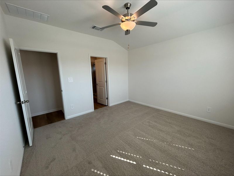Unfurnished bedroom with carpet floors, lofted ceiling, and a ceiling fan Unfurnished bedroom with carpet floors, lofted ceiling, and a ceiling fan