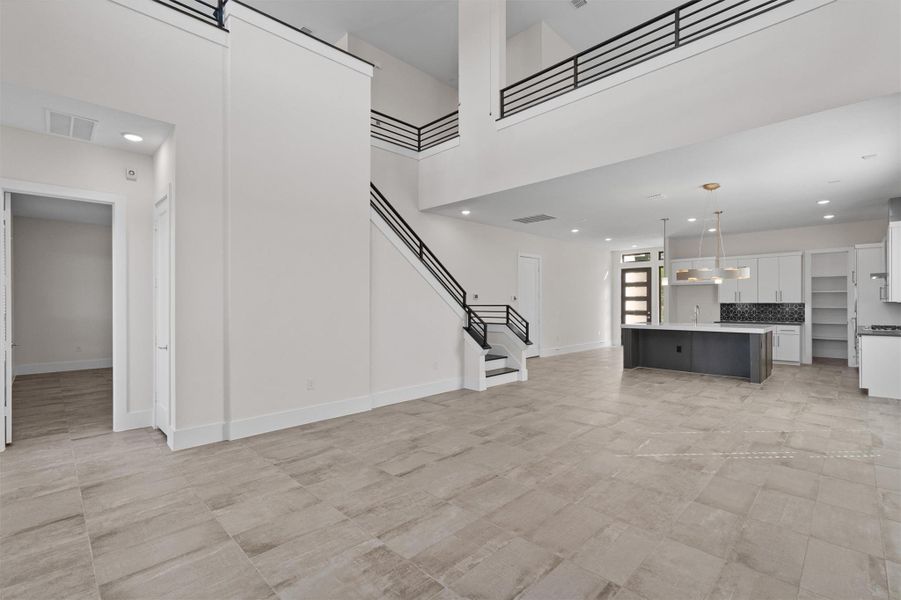 Unfurnished living room featuring recessed lighting, a high ceiling, and stairway Unfurnished living room featuring recessed lighting, a high ceiling, and stairway