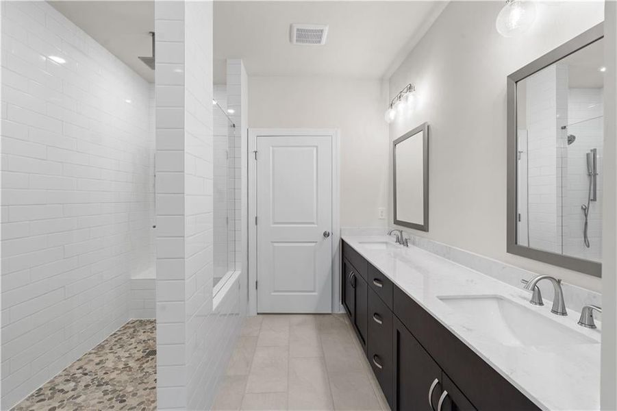 Bathroom featuring double vanity, a walk in shower, and light tile patterned floors