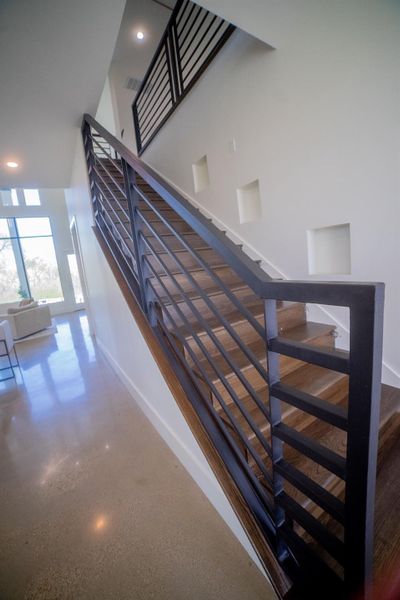 Make a grand entrance with a stunning modern staircase that serves as the home's architectural centerpiece. Featuring sleek black metal horizontal railings, the open design creates an immediate sense of sophistication and sets a contemporary tone from the moment you step inside