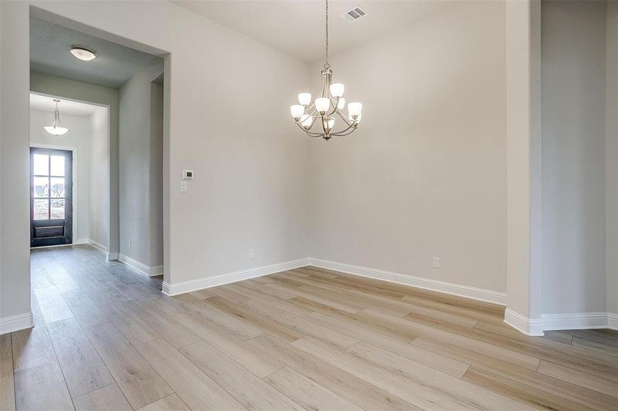 Spare room featuring an inviting chandelier and light hardwood / wood-style flooring