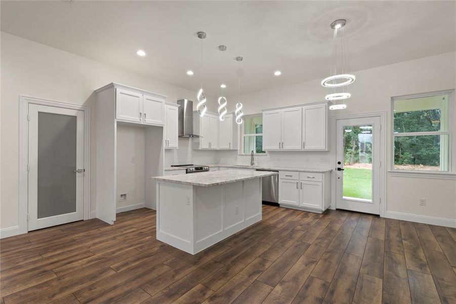 Spacious living area featuring wood-finish flooring, a modern ceiling fan, recessed lighting, and a contemporary fireplace with a wood mantle Spacious living area featuring wood-finish flooring, a modern ceiling fan, recessed lighting, and a contemporary fireplace with a wood mantle