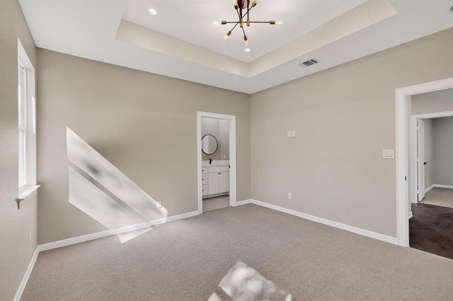 Unfurnished room featuring carpet flooring, a chandelier, and a tray ceiling Unfurnished room featuring carpet flooring, a chandelier, and a tray ceiling