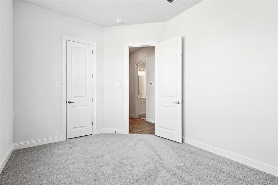 Unfurnished bedroom with light colored carpet and baseboards