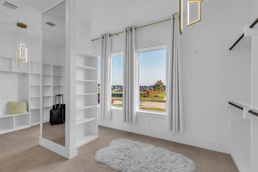 Primary Suite Dream Closet (Alternate View):Awash in natural light, this couture-inspired closet offers custom shelving, elegant display space, and full-length mirrors beneath designer lighting. A sanctuary for style, it transforms daily dressing into a luxurious ritual.