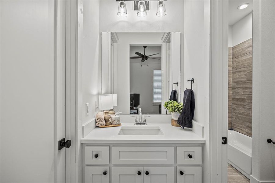 Bathroom featuring vanity, ceiling fan, hardwood / wood-style flooring, and tiled shower / bath combo