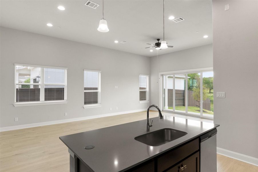 Kitchen featuring open floor plan, ceiling fan, a kitchen island with sink, light wood-style floors, and dishwasher