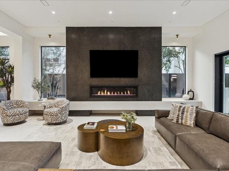 The living room is defined by a stunning large-scale tile wall centered around a 70-inch gas fireplace, creating a striking modern statement.