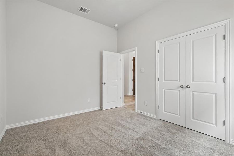 Unfurnished bedroom with light colored carpet and a closet Unfurnished bedroom with light colored carpet and a closet