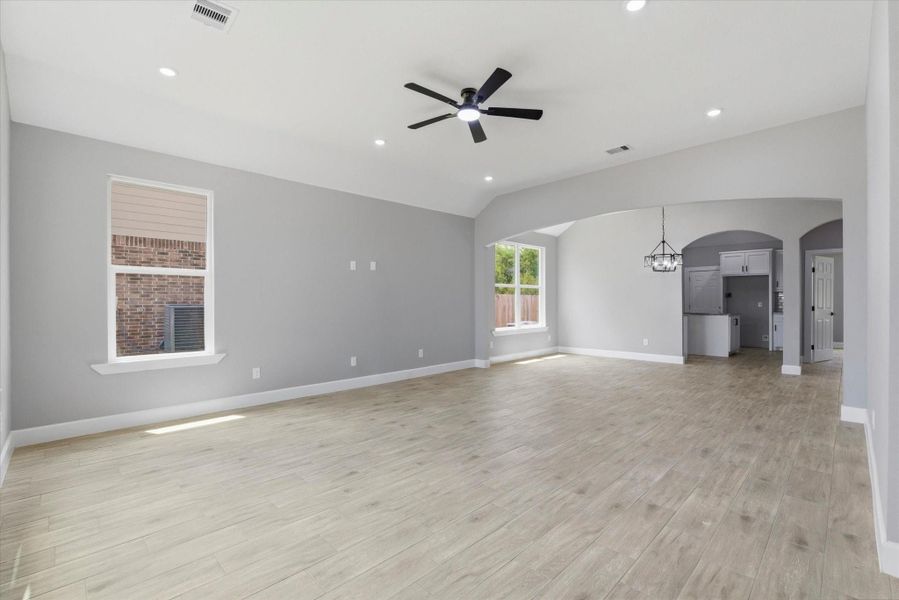 Come on in! Light-filled living area featuring soaring vaulted ceilings, recessed lighting, and wood-look tile flooring.
